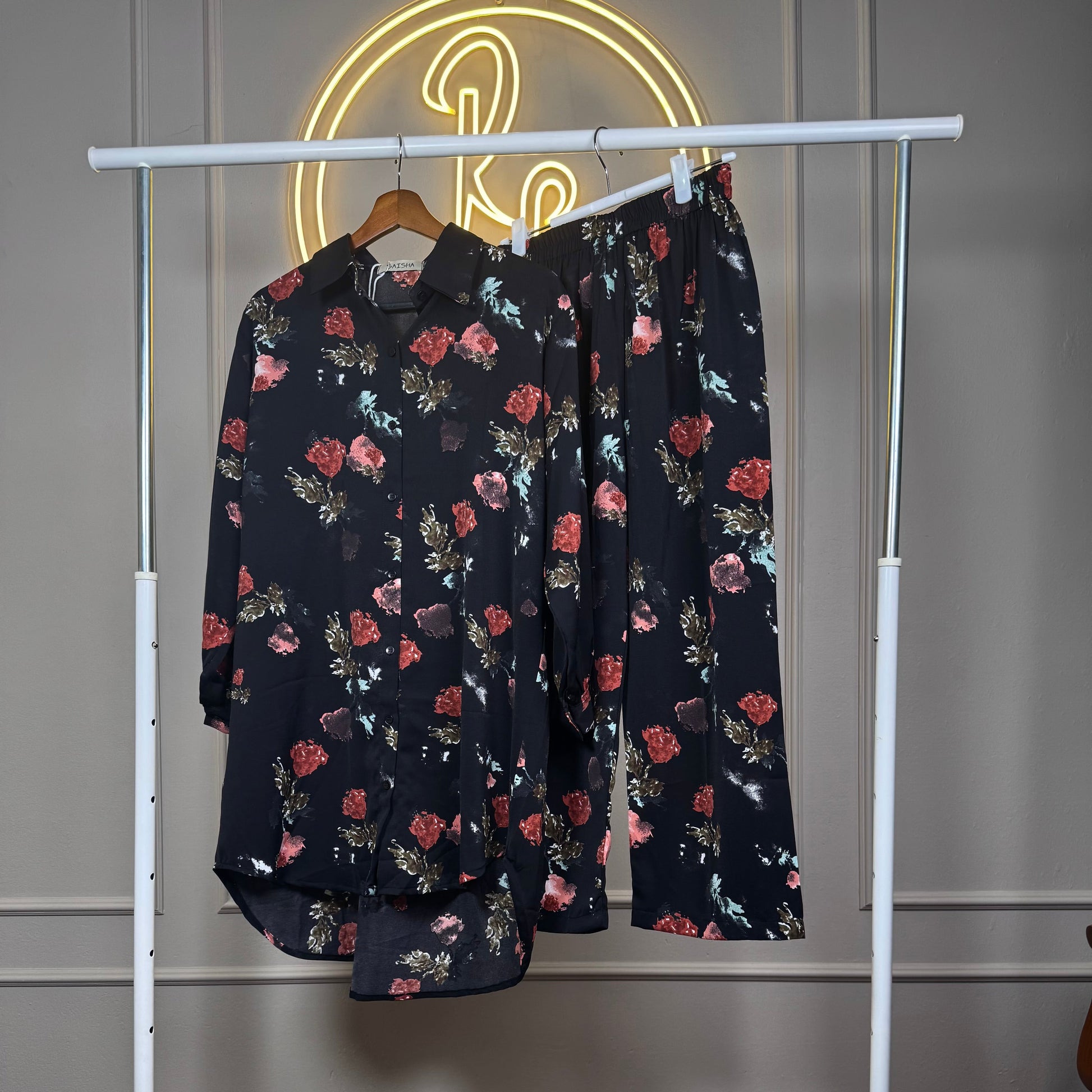 Floral-patterned shirt and pants on a white rack against a neutral wall.