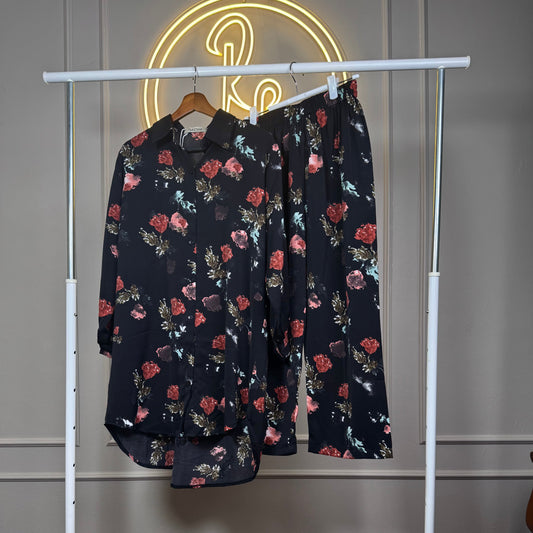 Floral-patterned shirt and pants on a white rack against a neutral wall.