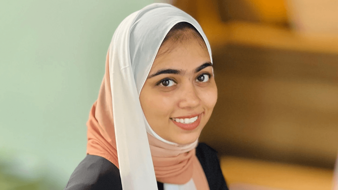 Woman wearing a ombre hijab smiling in front of a blurred background