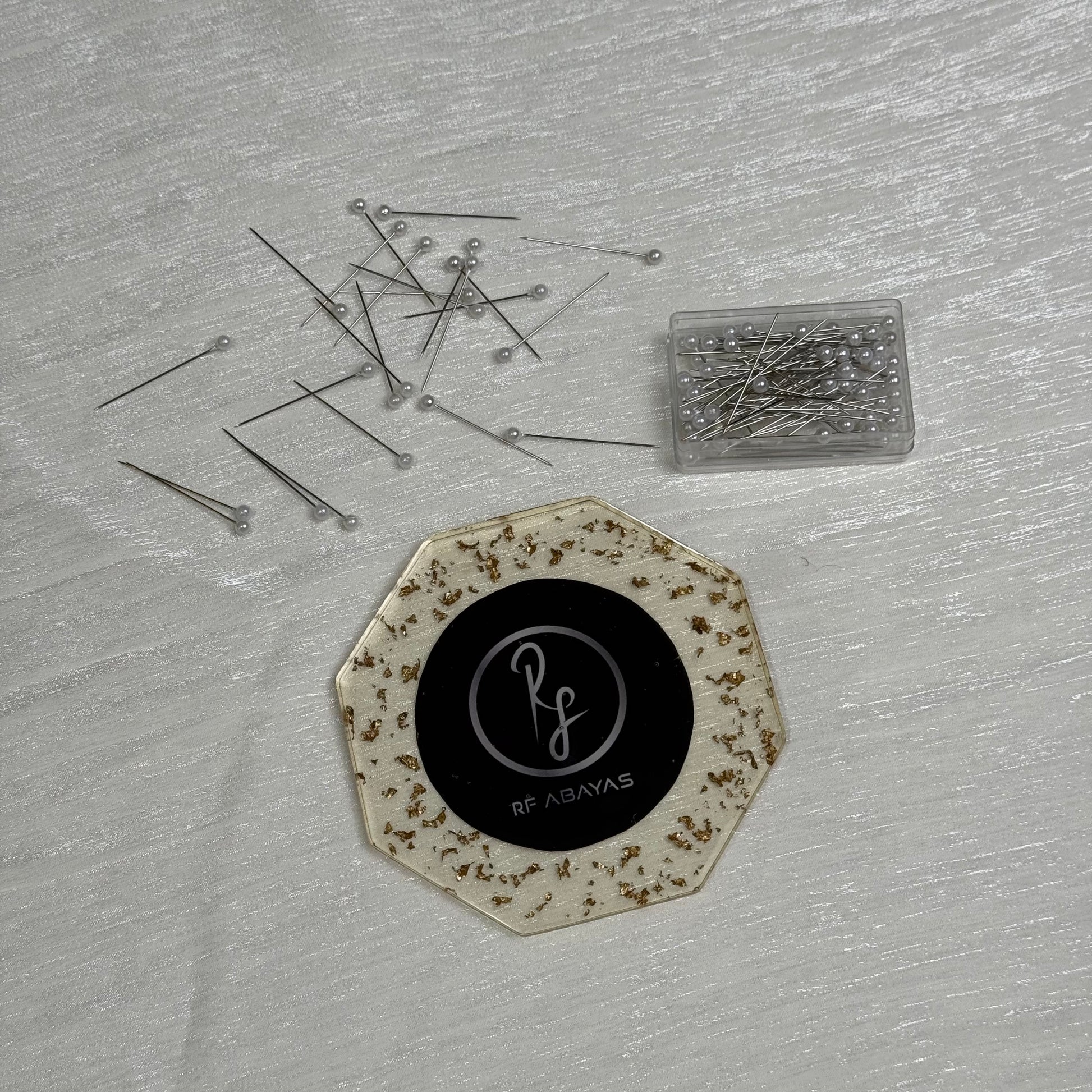 Black RF Abayas hijab pin box with multiple hijab pins displayed, designed for securing hijabs in stylish, functional ways.